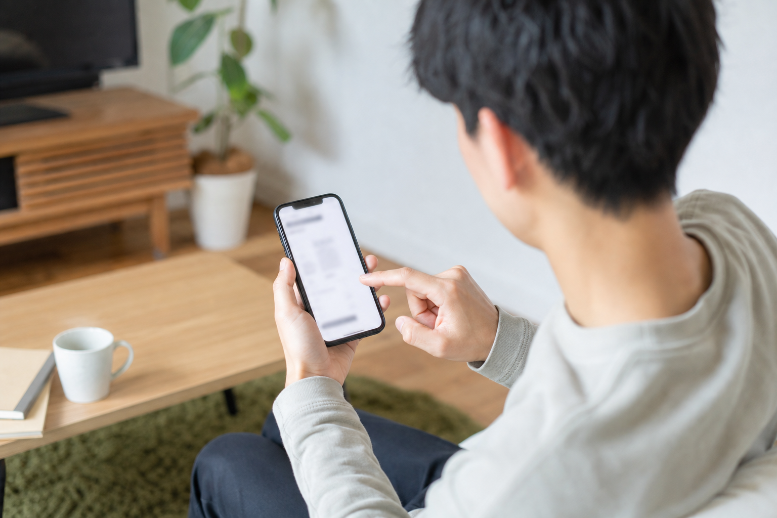 単身者のスマホ相談：名古屋・愛知で賃貸契約の初期費用をクレジットカード／後払い・分割で支払いたい。見積書を見て『どの費目がカード／分割／後払い対象か』を自分で判断する方法と、不動産会社へ聞く具体的質問例を知りたいについて一人でスマートフォン確認をする場面を斜め後方から撮る。画面はぼかし、手元中心、カップルなし