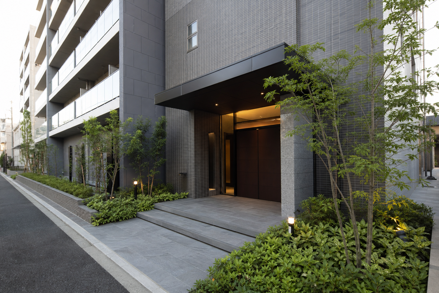 賃貸マンション外観：名古屋・愛知で学生（親が連帯保証人になれない／実家が遠方で印鑑証明を出せない）が賃貸申込をする際、審査を通すために準備すべき書類・順序・不動産会社への伝え方を知りたいの判断先を象徴する現代的な賃貸マンション入口を道路側から広角で撮る。人物、看板、読める文字なし