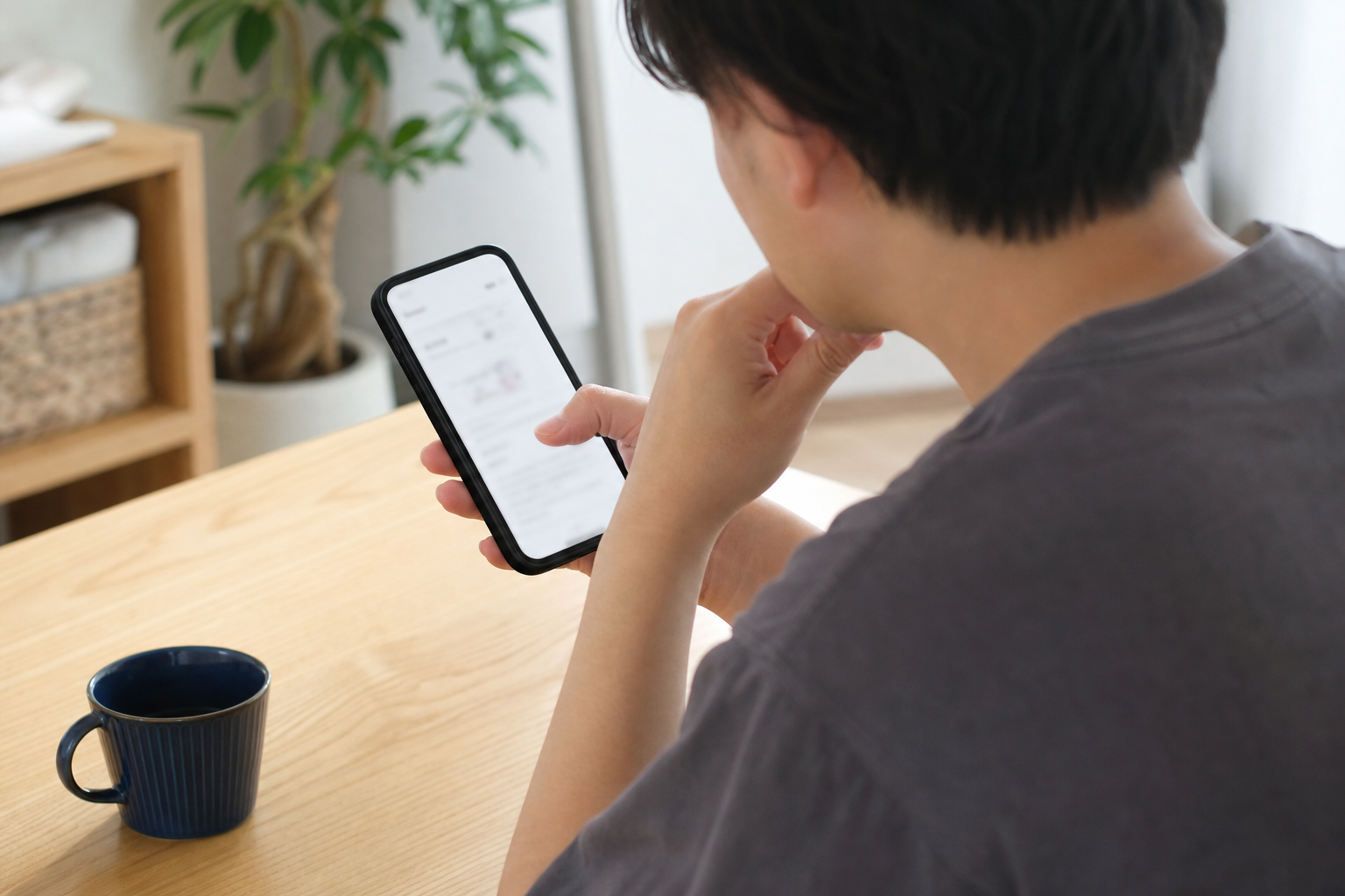 単身者のスマホ相談:名古屋・愛知で退去後に管理会社からエアコンクリーニング代を請求された。精算明細をどう読み、まず何を請求(証拠)要求すれば減額や不当請求の指摘につなげられるかを知りたいについて一人でスマートフォン確認をする場面を斜め後方から撮る。画面はぼかし、手元中心、カップルなし